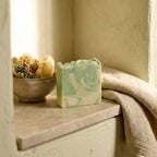 Degleri jasmine pure olive oil soap bar resting on a bathroom shelf niche with a natural sea sponge and linen towel
