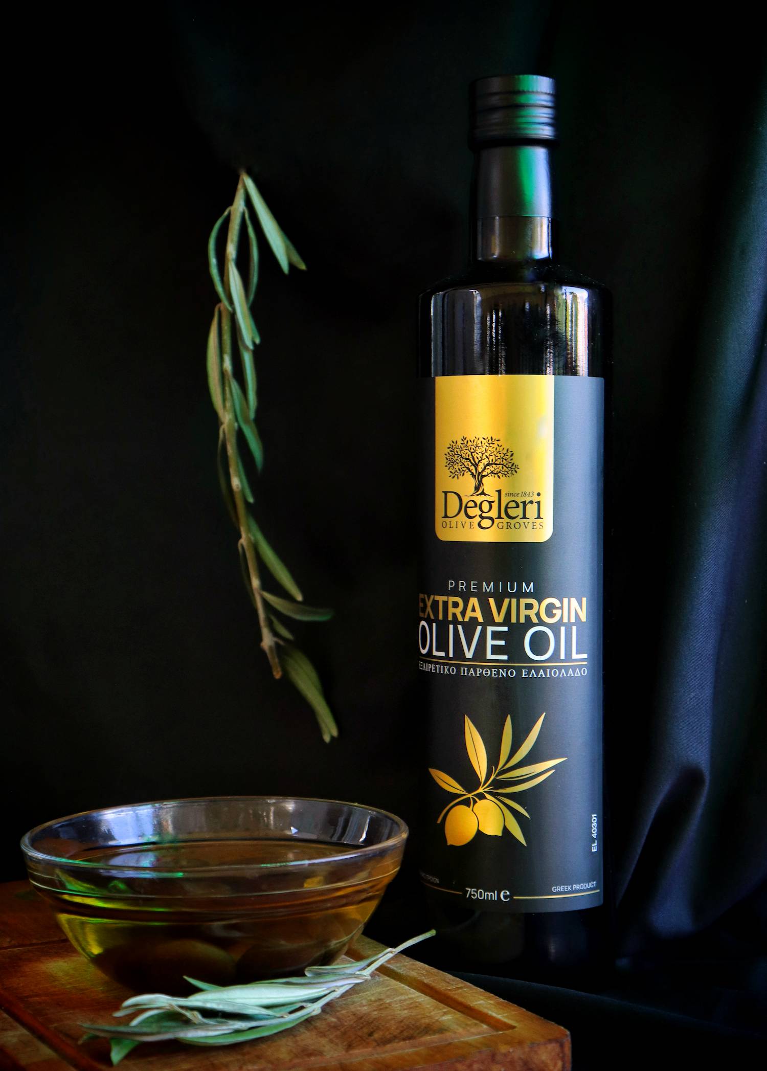 A bottle of Degleri Premium Greek Extra Virgin Olive Oil alongside a small bowl of olives and olive oil.